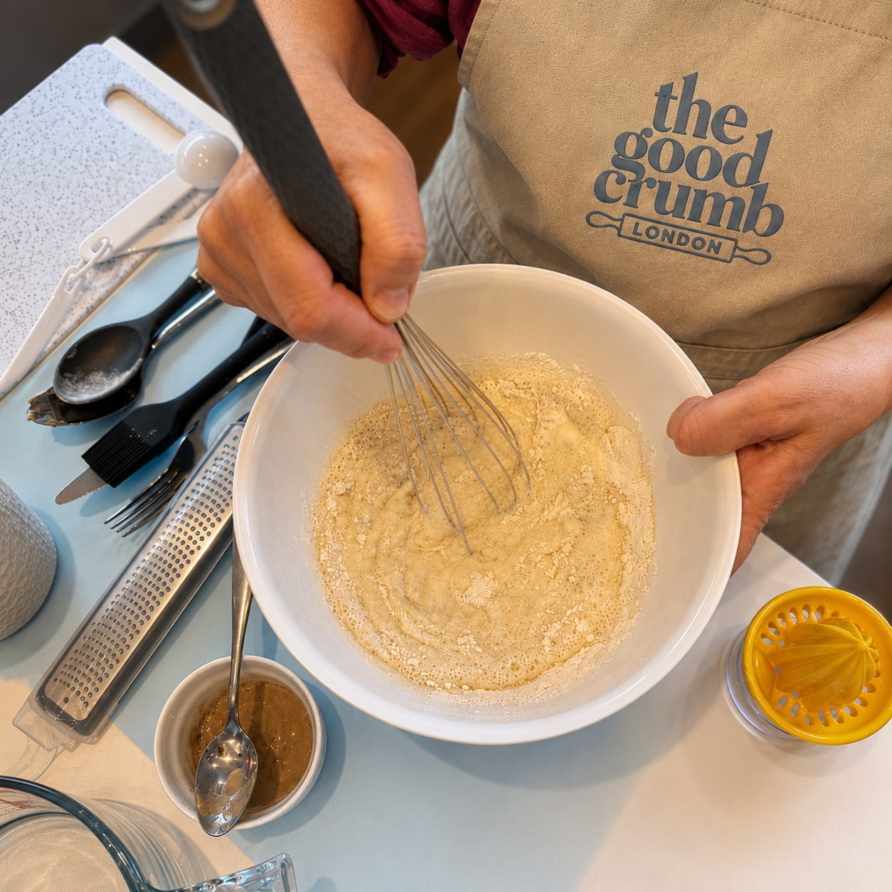 A close up of a bowl filled with crumpet batter being whisked