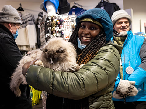 A traveller holding a cat in their arms and smiling