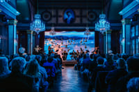 Live classical concert Vienna with blue lighting, crystal chandeliers, ballet multimedia projection and full audience