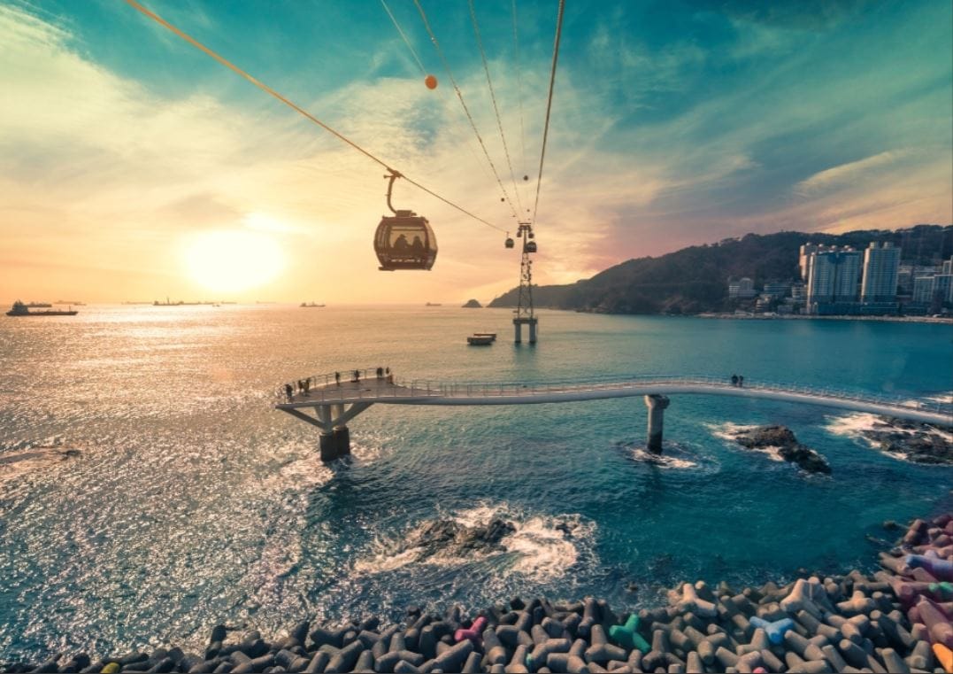 A cable car crosses over the sea at sunset near Songdo Marine Cable Car