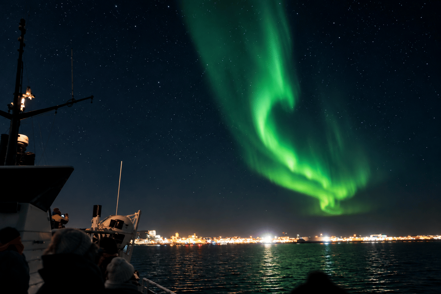 A vivid green Northern Lights display seen from a boat off the coast of Reykjavík.