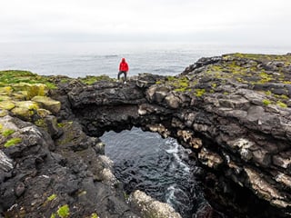 Traveller standing on rocks in Hafnaberg in Reykjanes, Iceland.