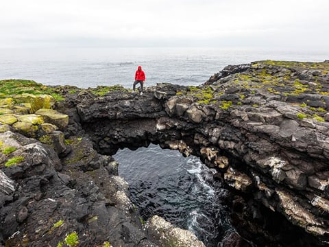 Traveller standing on rocks in Hafnaberg in Reykjanes, Iceland.