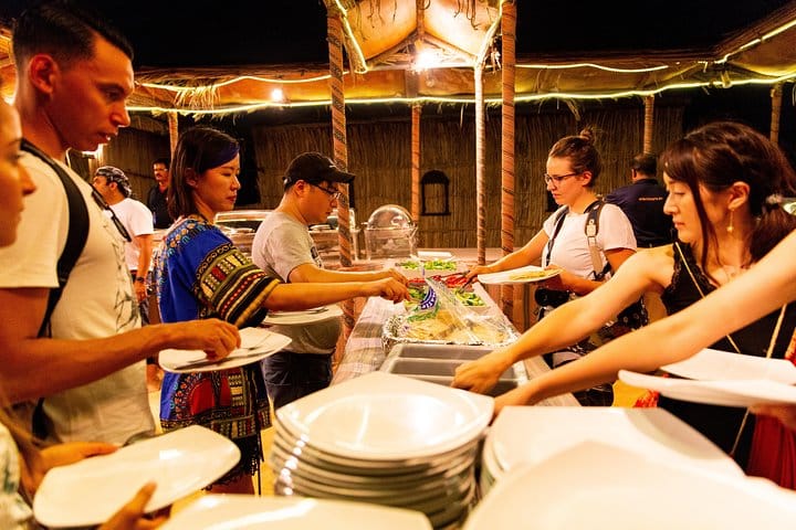 Travelers serve themselves food at a desert camp while on safari near Dubai.