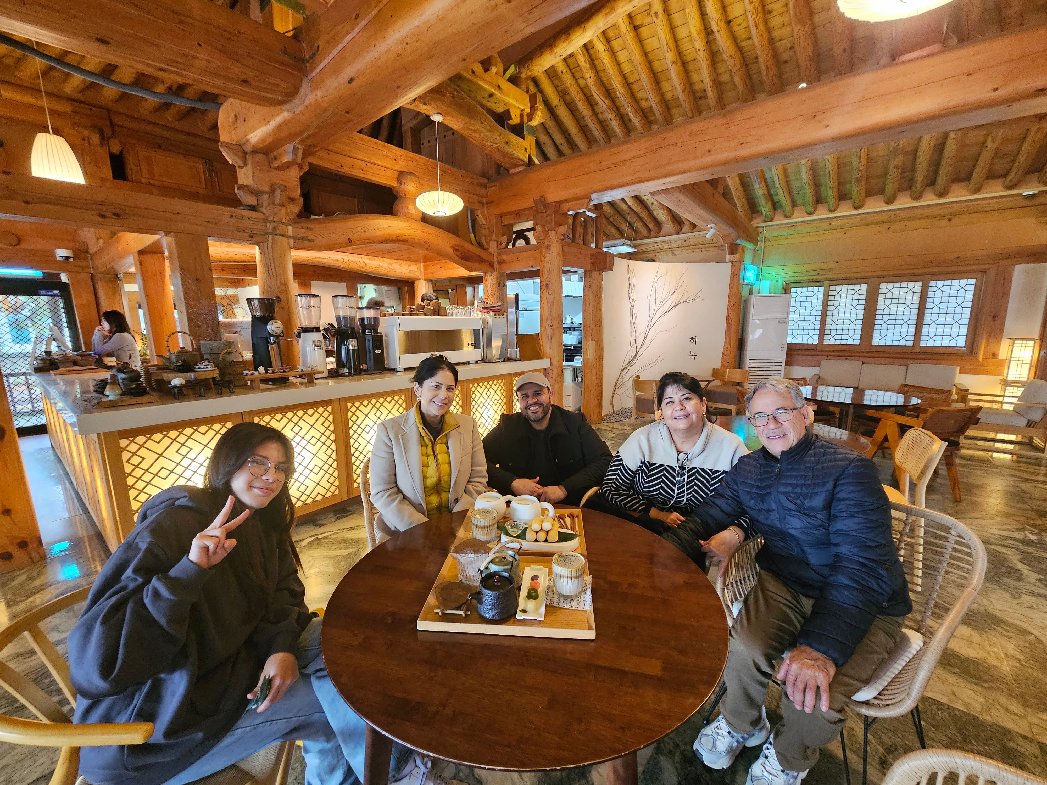 A group sits together around a table inside Ha:nok Cafe, a traditional hanok-style cafe with wooden beams.