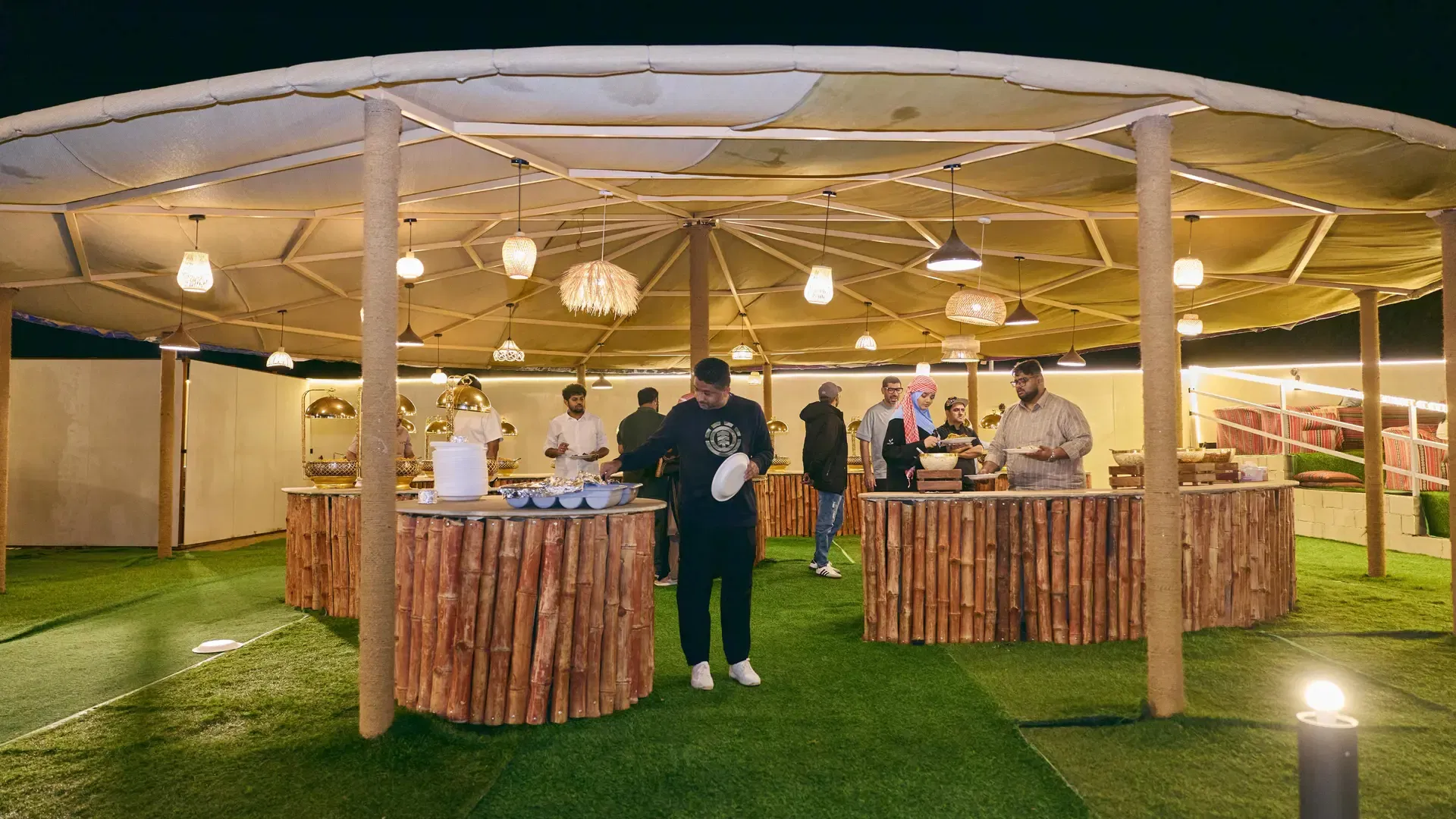 Guests select food from a buffet line under a large canopy at Desert Safari + Al Faqaa Camp.