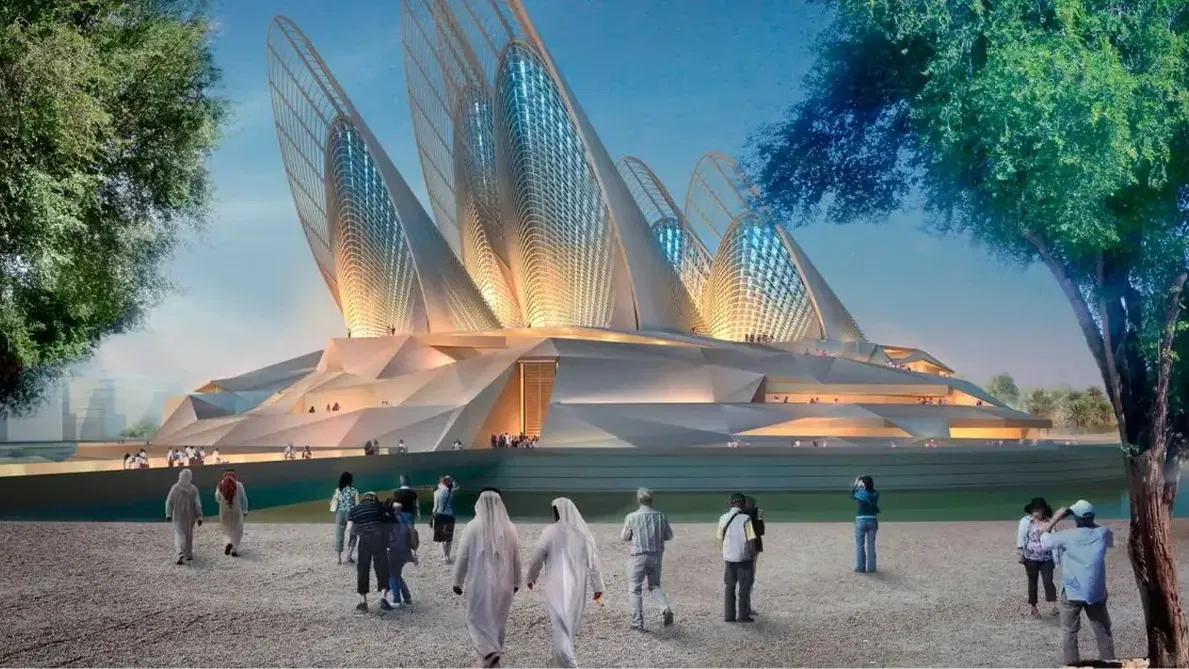 Visitors walk on a gravel path toward a large building with wing-shaped structures at Zayed National Museum, Abu Dhabi.