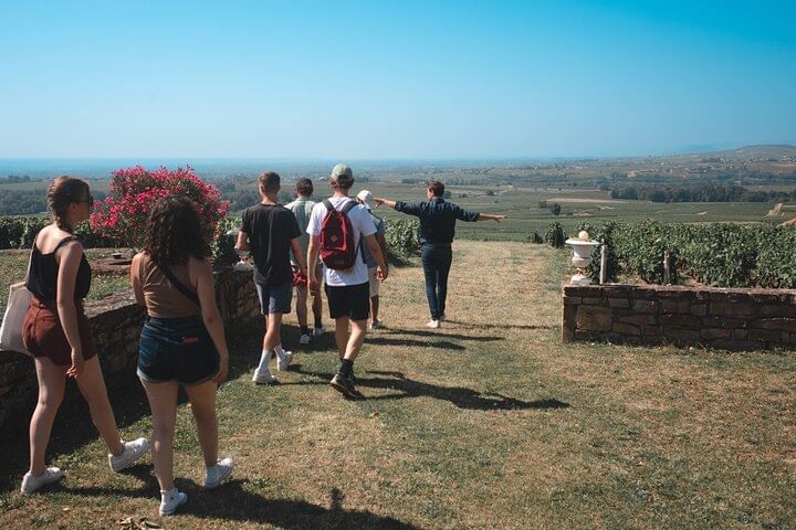 A group of people walking in a garden out to the open landscape of Beaujolais