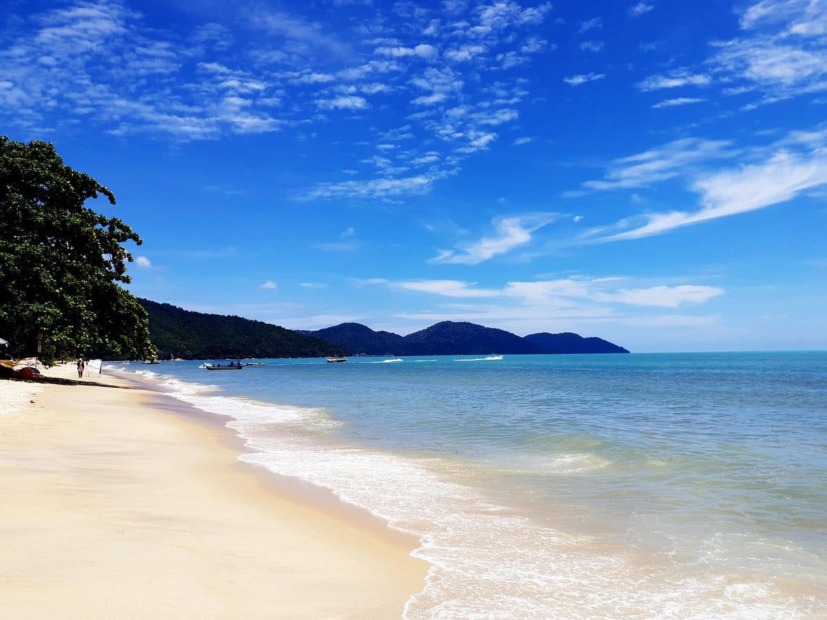 شاطئ باتو فرنجي الشهير في جزيرة بينانج، ماليزيا، بمياهه الزرقاء الصافية ورماله الذهبية الناعمة، مثالي للأنشطة المائية والاسترخاء