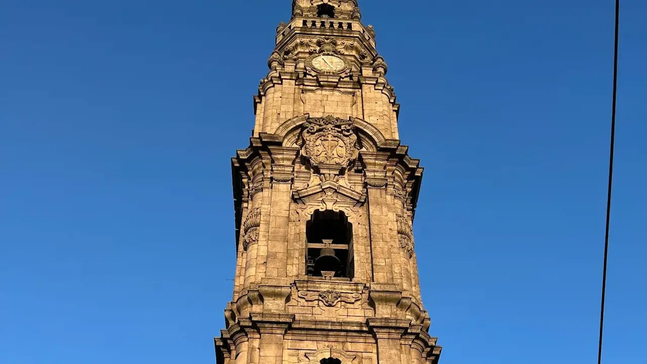 A close-up view of the ornate stone bell tower rises against a clear blue sky at Clérigos Tower & Museum Ticket.