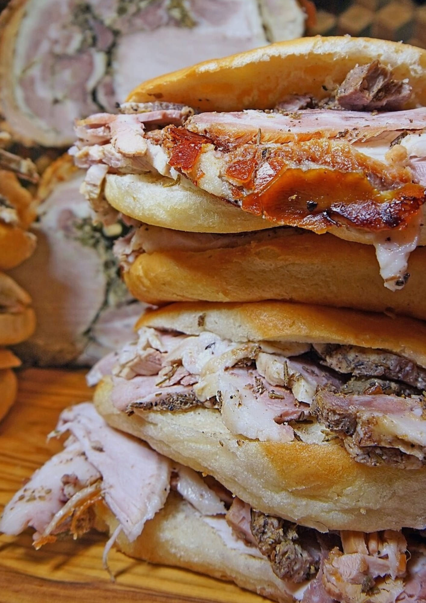 Close-up of a porchetta sandwich in a crusty roll, with tender roast pork and crisp crackling.