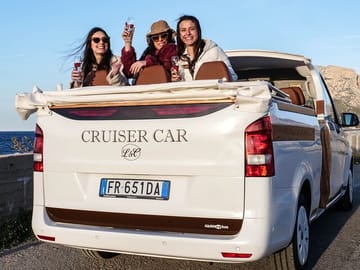 Panoramic view of a tour cruising along the rugged Sicilian coast near Palermo, with tourists admiring the view.