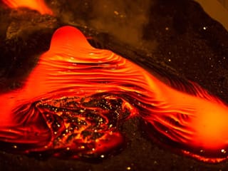 Bright red molten lava flowing during a live demonstration that recreates the intensity of a volcanic eruption in Iceland.