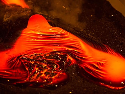Bright red molten lava flowing during a live demonstration that recreates the intensity of a volcanic eruption in Iceland.
