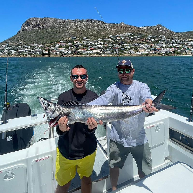 Proudly displaying the catch amidst Simon's Town's scenic shoreline.