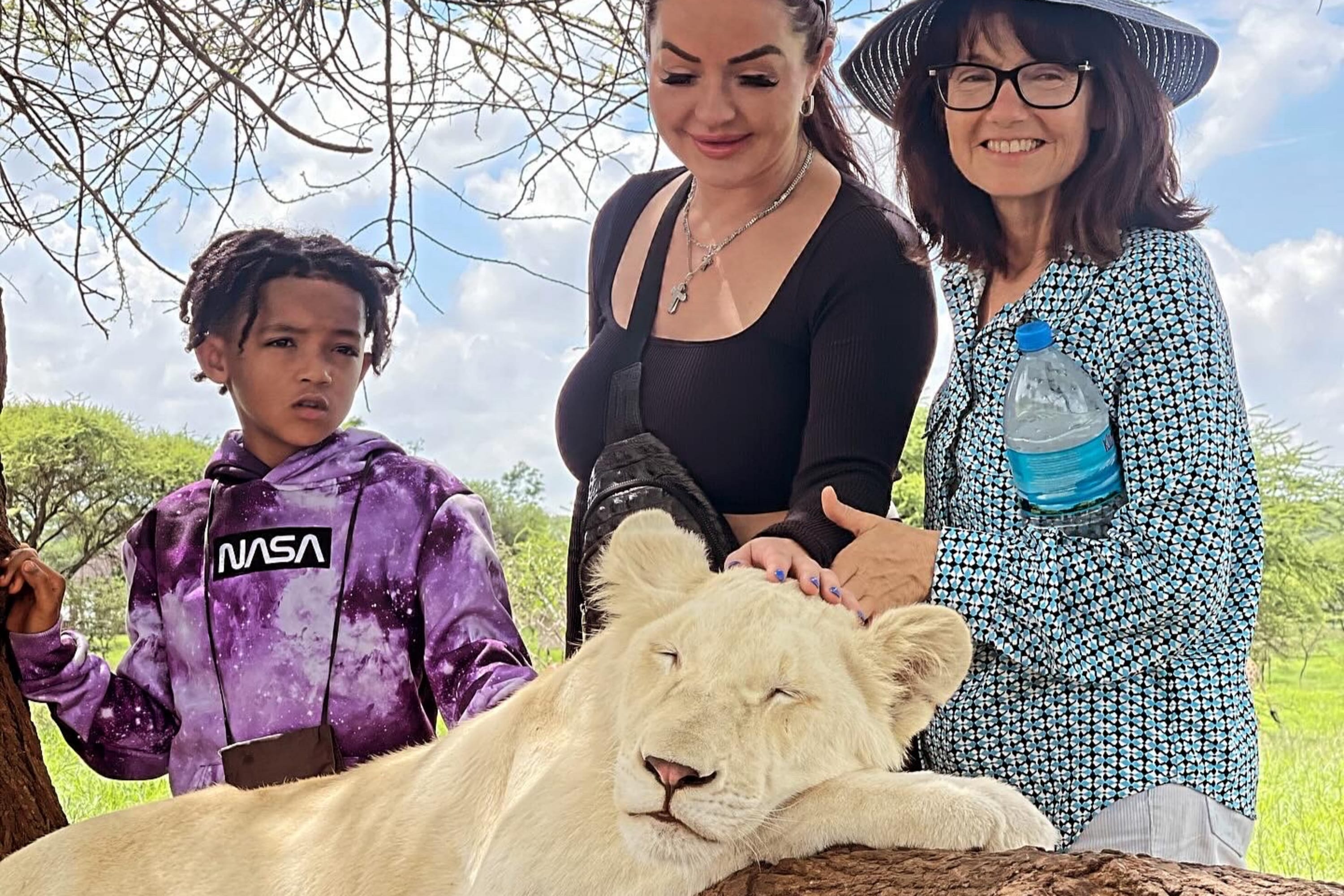 ​A family sharing a private moment with a white lion in an exclusive sanctuary.