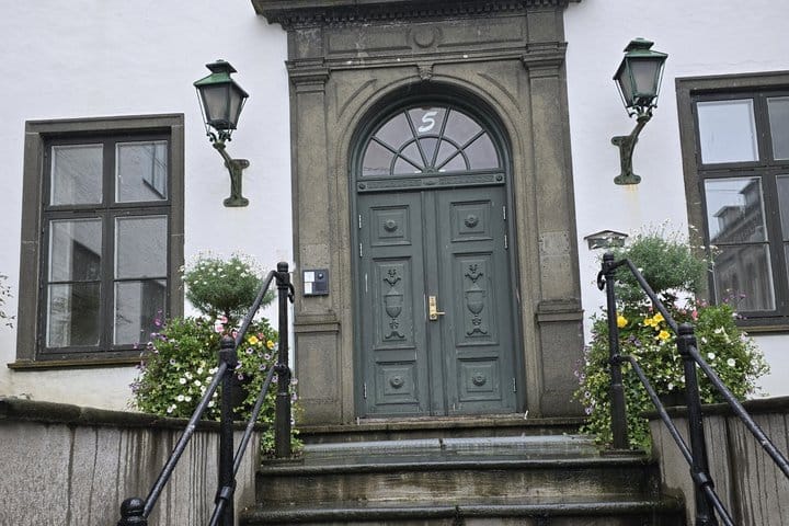 Ornate grey doorway with flower baskets on a historic Bergen house