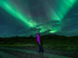 A womand standing under the Northern Lights in Iceland
