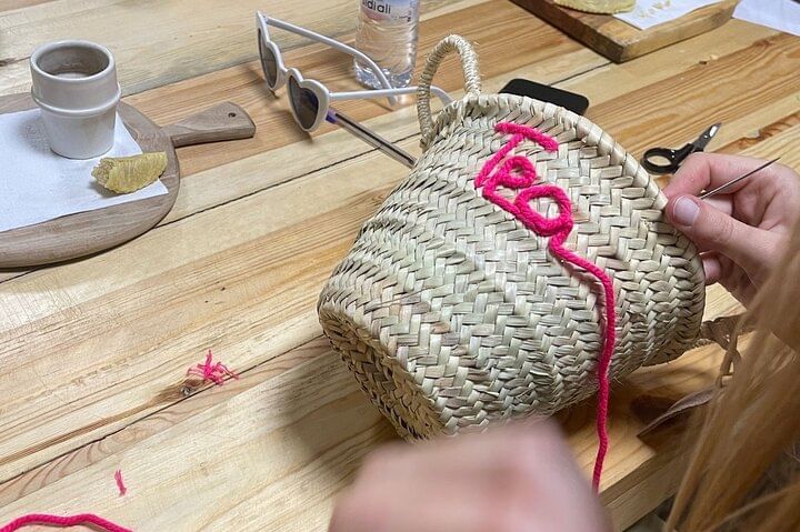 Close-up of a small palm-leaf basket hand-embroidered with the word