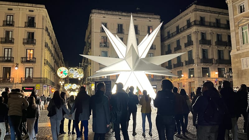 A giant lit star on a square in Barcelona's old town at night