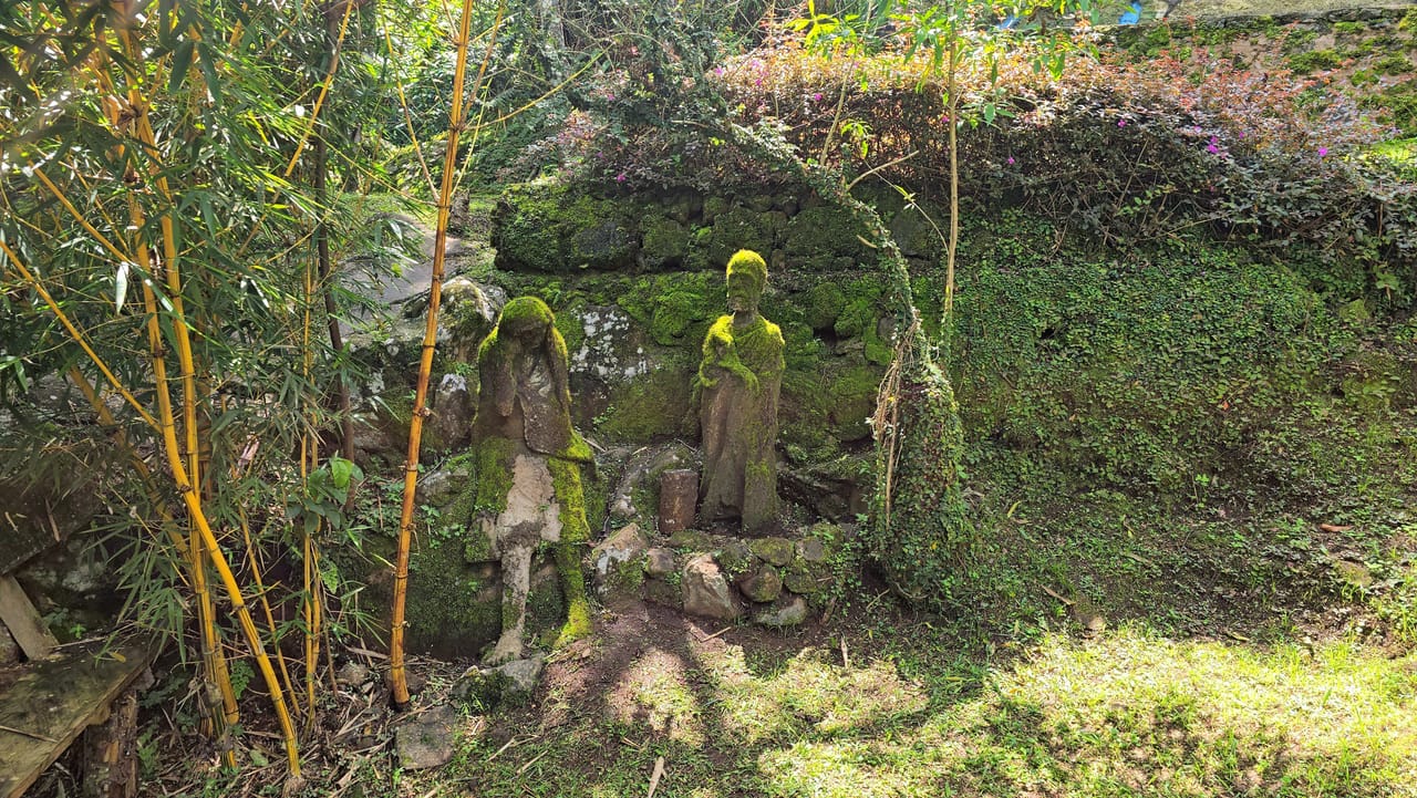 Historical stone entrance to the Chagga defense caves surrounded by lush green vegetation in Marangu, Kilimanjaro.