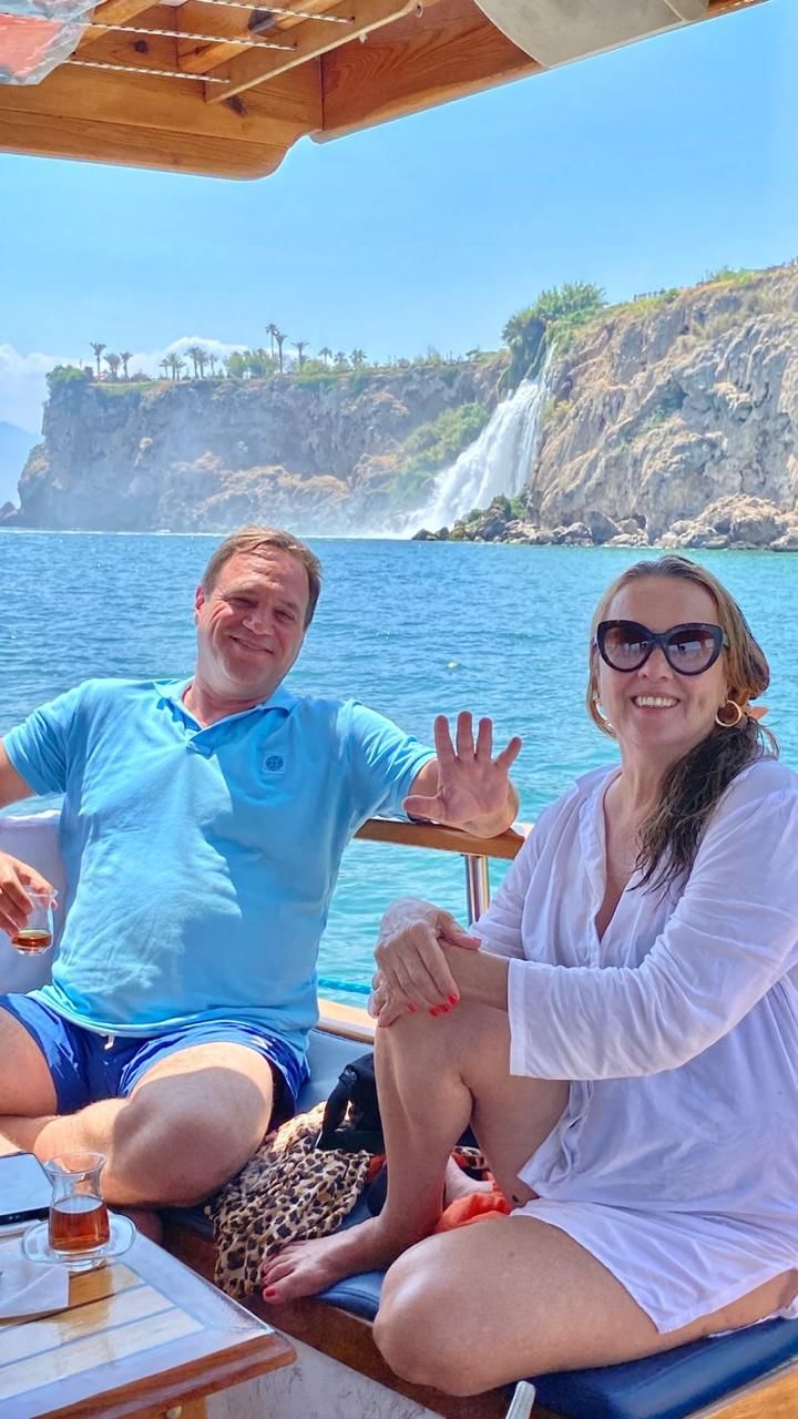 “Our tour guide standing on a boat with travelers during a scenic cruise along Antalya’s rocky coastline and clear blue waters.”