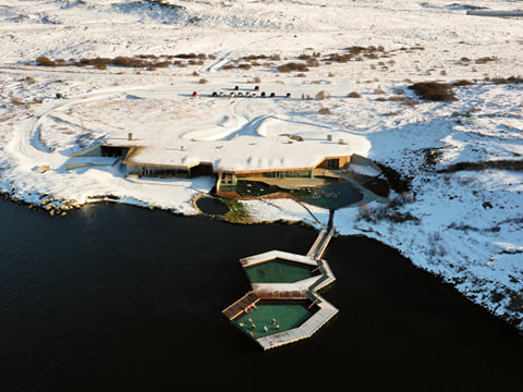 A picture showing Vök baths geothermal pools in their winter clothing covered in snow.
