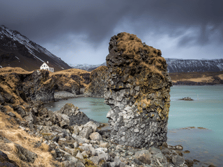 Arnarklettur sea rock with the house Arnarstapi in the background