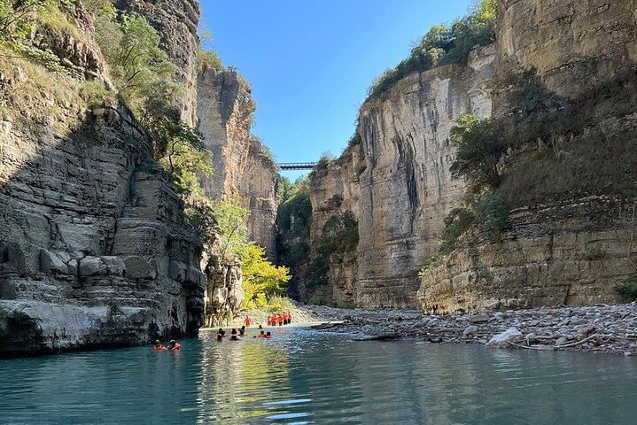 Visit rocky cliffs of the Osumi River Canyon with a bridge crossing above .