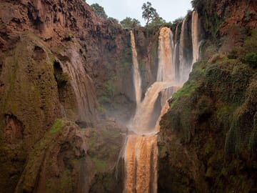 Reddish muddy water rushes down Ouzoud Falls outside of Marrakech.