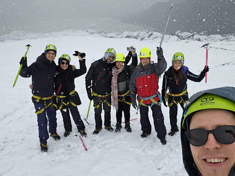 People taking a selfie on the glacier as it is snowing.