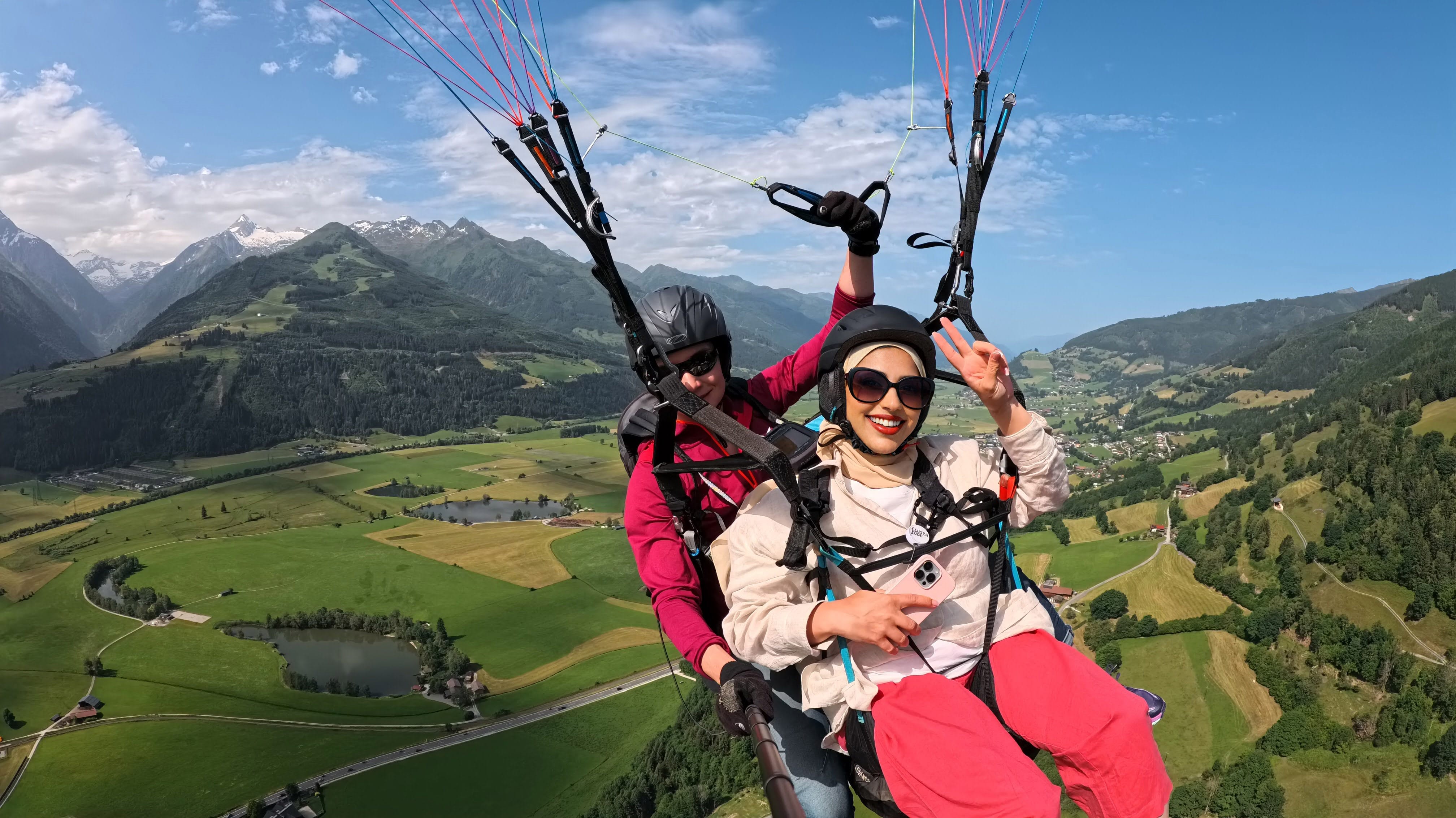 Arabic Muslim woman paragliding with a female tandem pilot over Zell am See, Austria