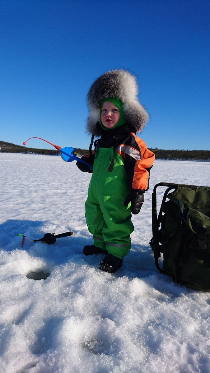 A kid trying ice fishing with a cozy and warm overall.