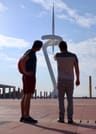 The guide is explaining his guest the telecom tower on the Montjuic hill. The tower is like a white needle.