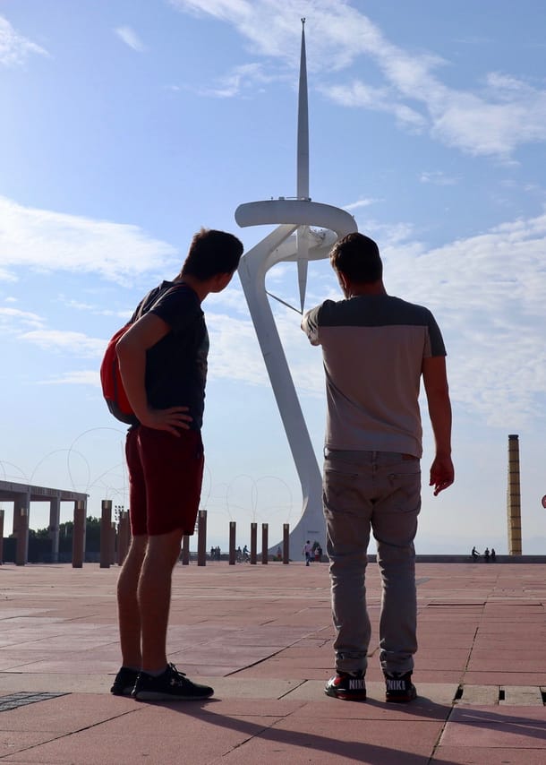 The guide is explaining his guest the telecom tower on the Montjuic hill. The tower is like a white needle.