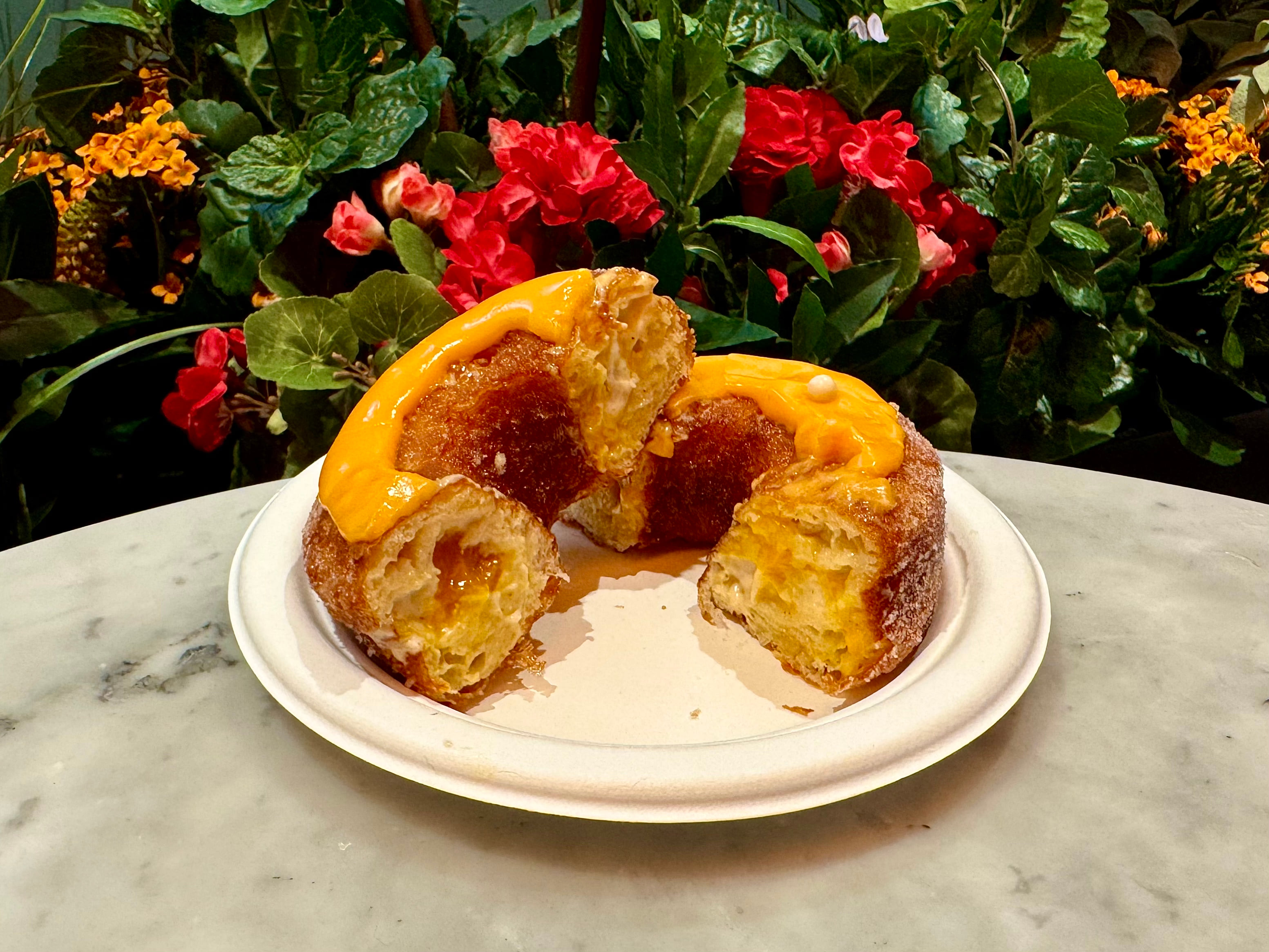 Pieces of a flaky glazed Cronut pastry arranged on a white plate.