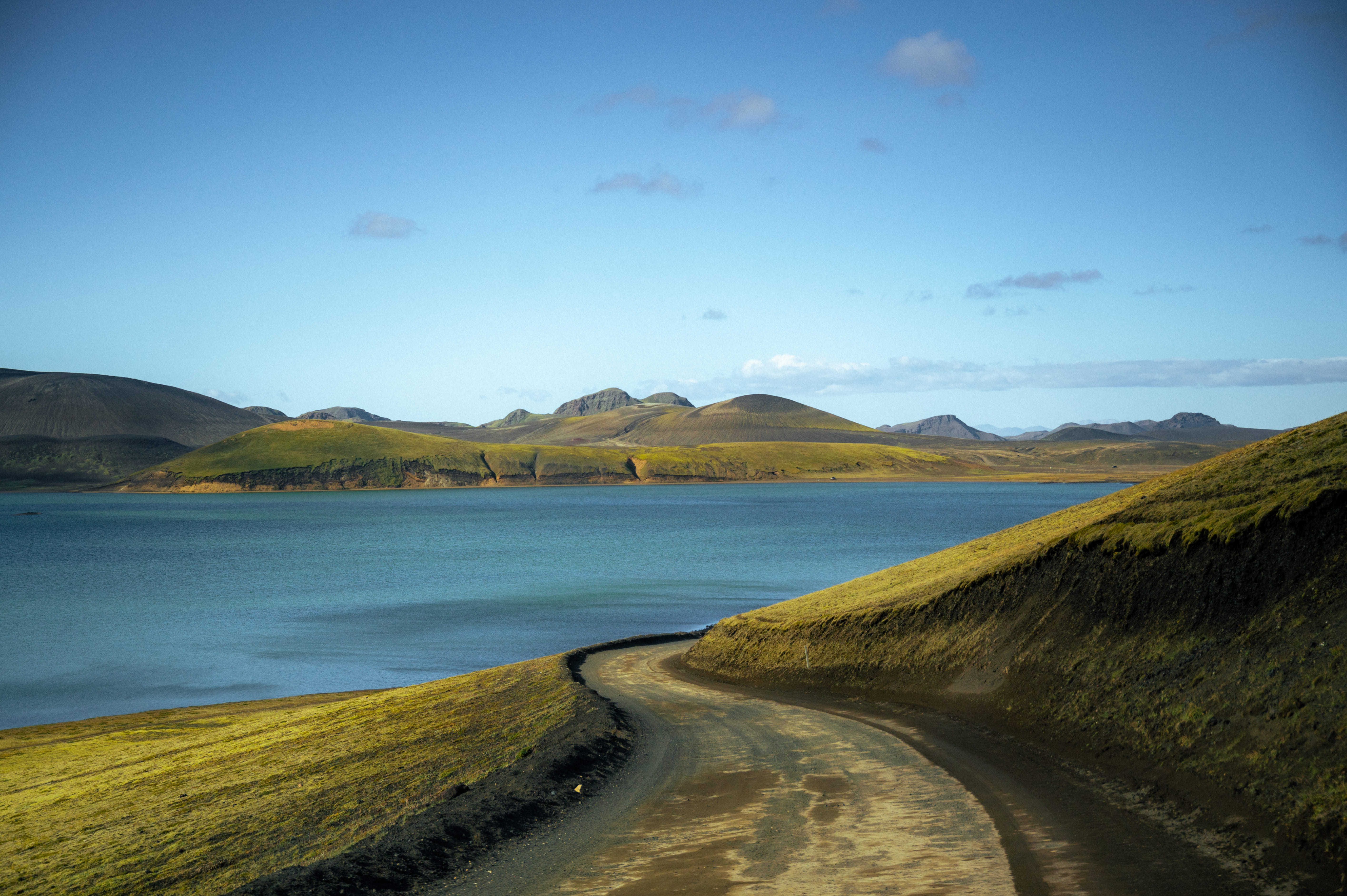Dramatic contrast of red volcanic slopes and blue water at Hnausapollur crater lake