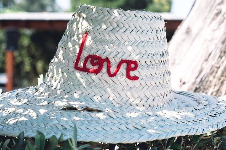 Traditional Moroccan straw hat displayed outdoors, embroidered with the word
