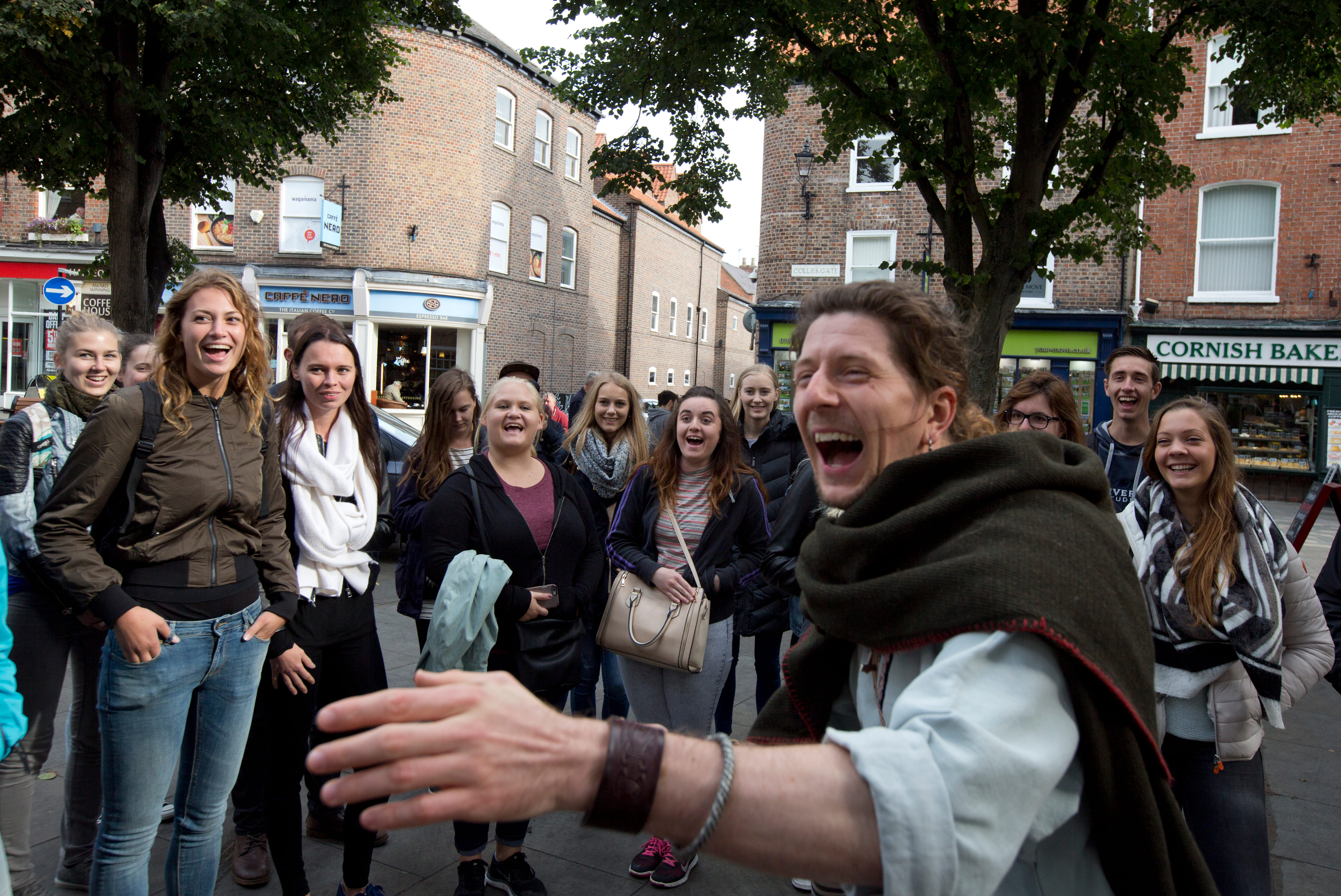 A viking with a group of laughing students having a nice time at King's Square, York.