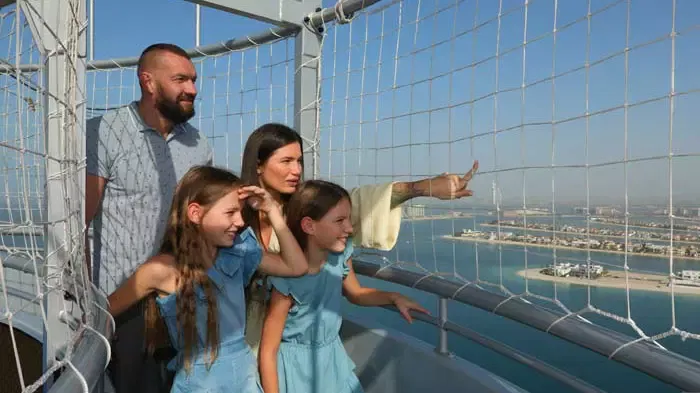 A family of four looks out through the safety netting of the observation deck of the large tethered helium balloon at The Dubai Balloon at Atlantis.