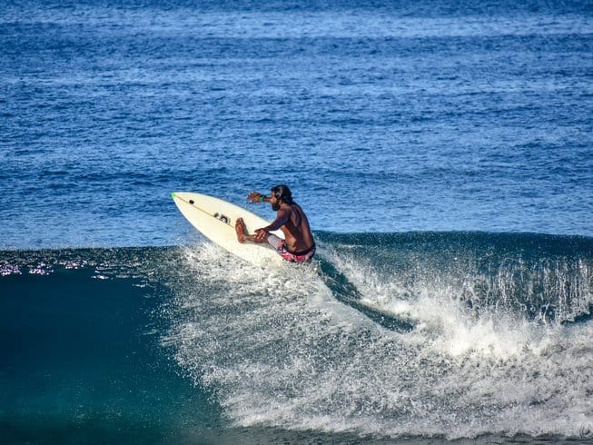 A surf instructor riding a wave at Thoondu Beach in Fuvahmulah.