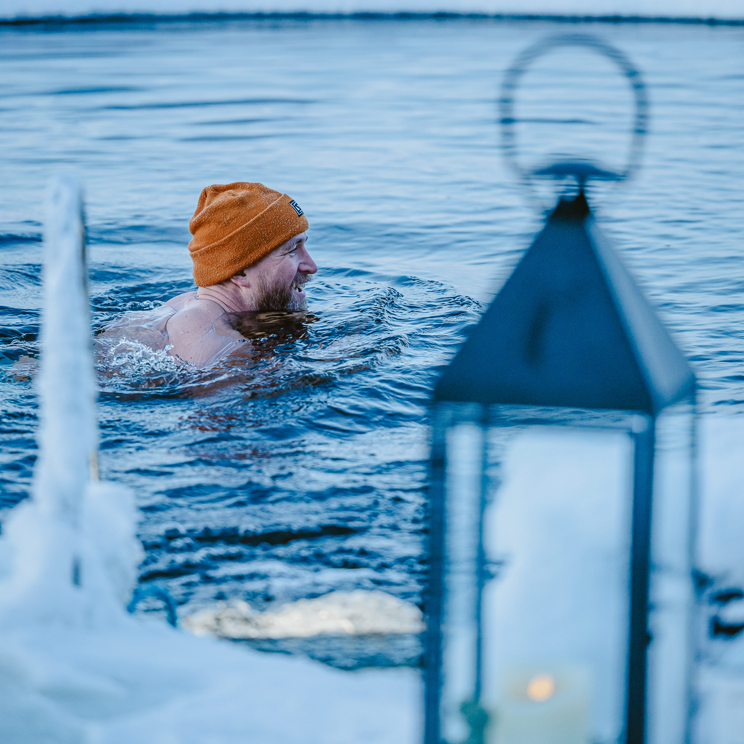 A man swimming surrounded by snow and ice.