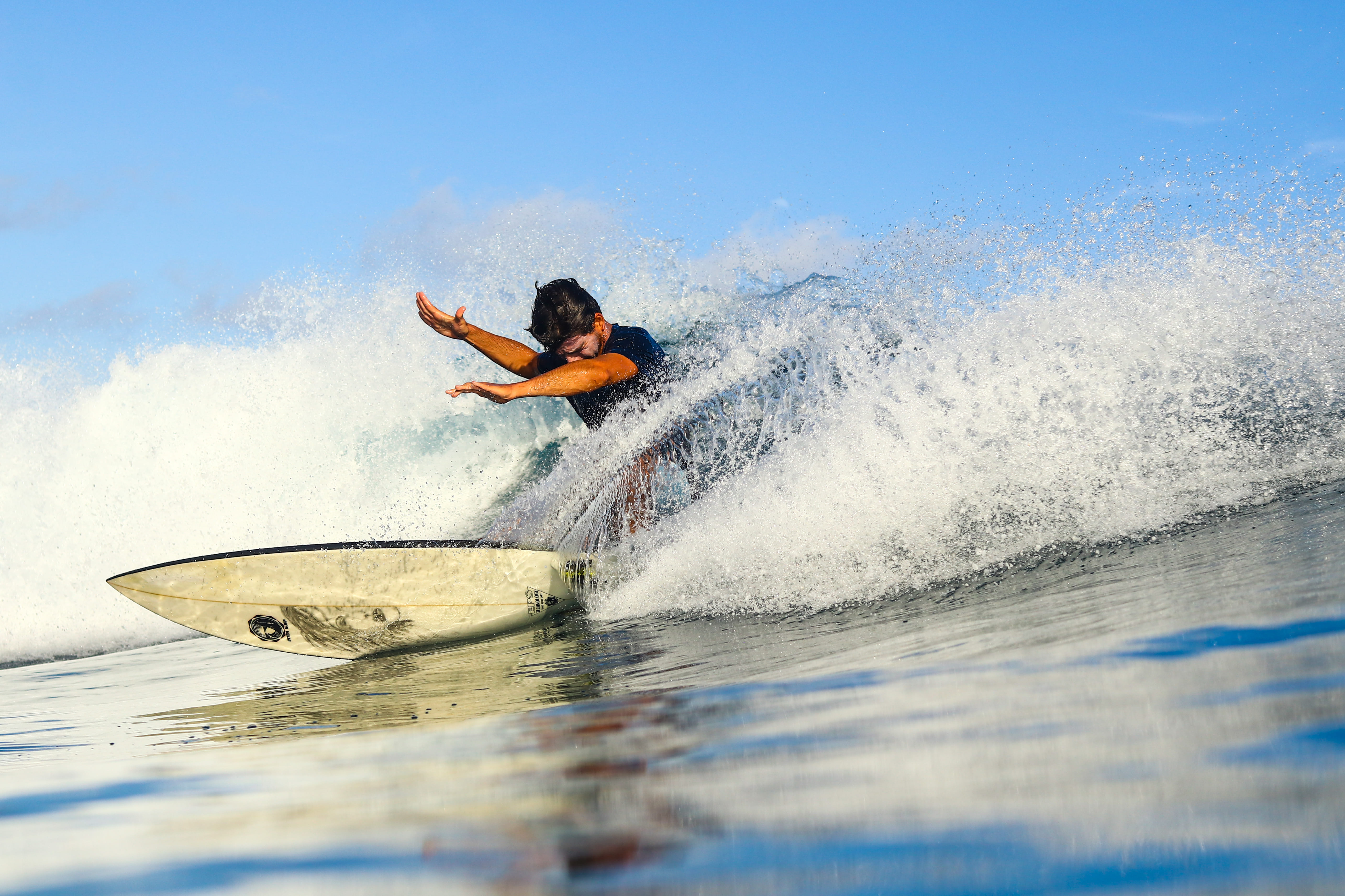 A surfer riding waves at Jailbreaks in Himmafushi, with a tour organized by ForBeyond Travel.