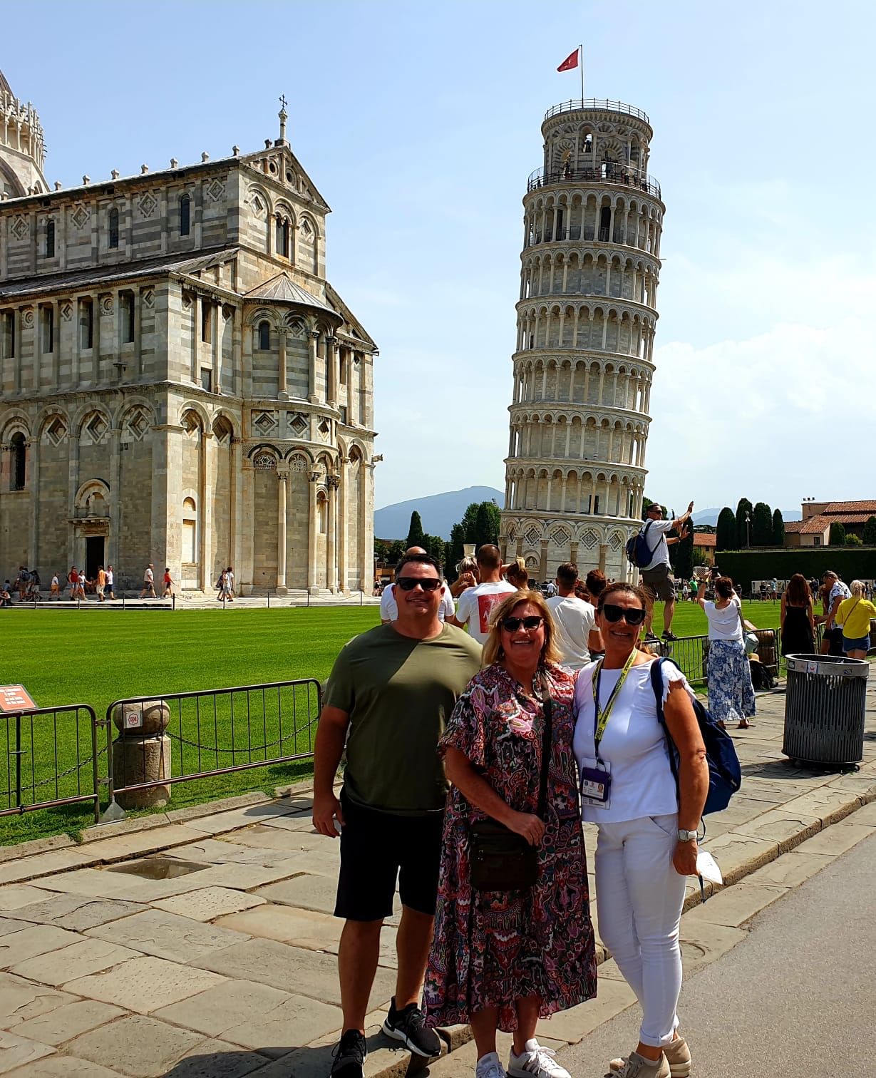 Some tourists in Piazza dei Miracoli in Pisa with the Cathedral and the Leaning Tower in the background 