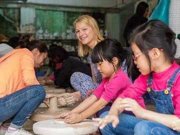 Tourists and 2 kids make pottery on their own with the instructions of our artisans