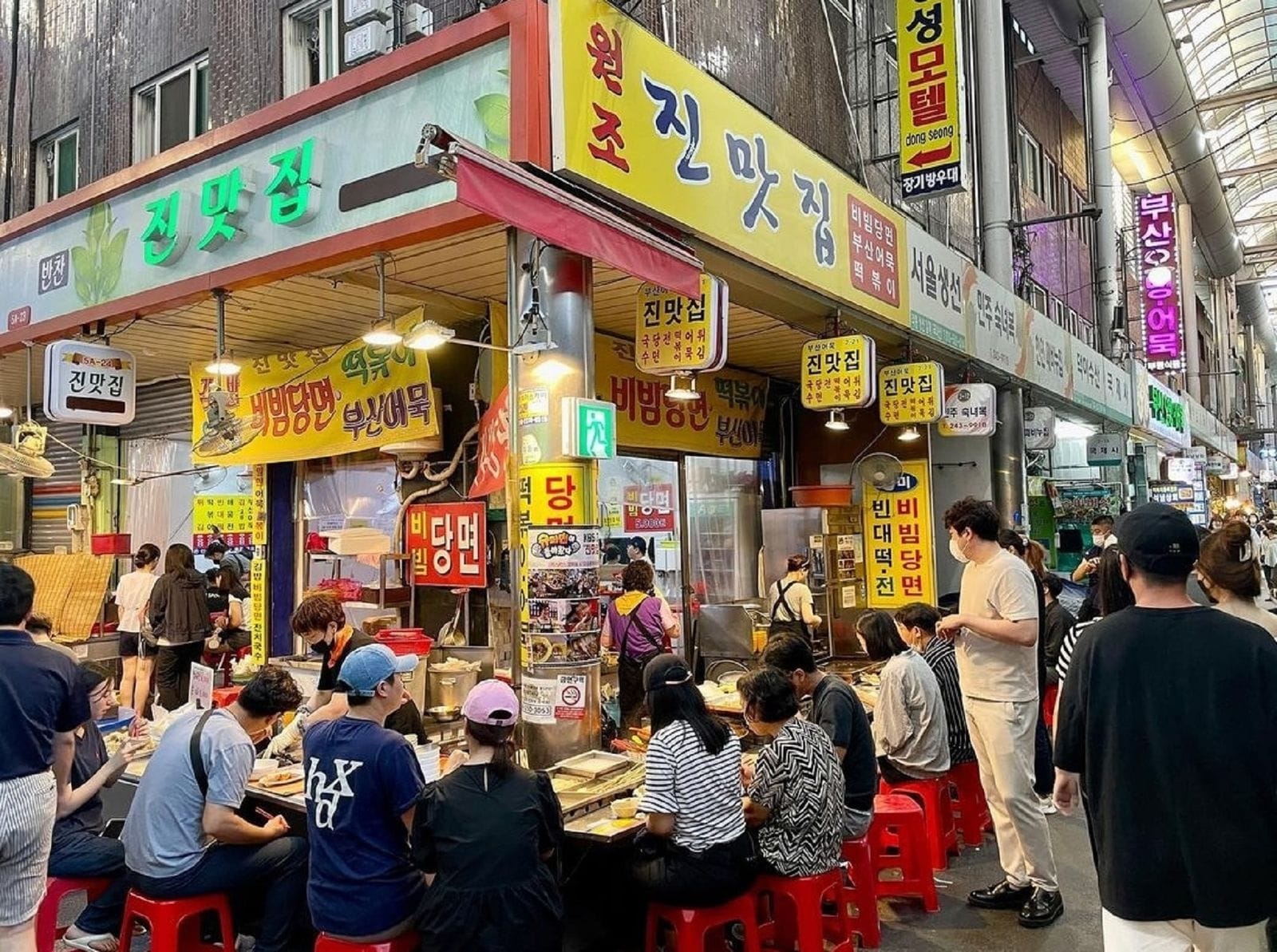 People eating Korean street food inside Bupyeong Kkangtong Market in Busan.