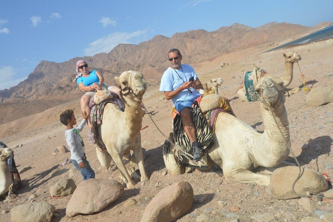 Two customers finish their camel ride and take memorial photos.