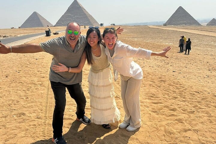 Tourists posing playfully in front of the Pyramids of Giza.