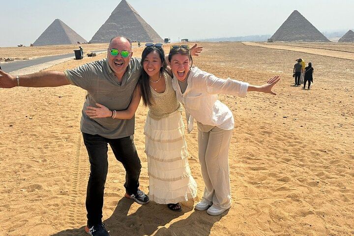 Tourists posing playfully in front of the Pyramids of Giza.