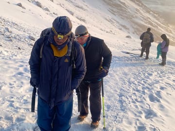 Hikers navigating a steep, snowy mountain slope during a high-altitude expedition.